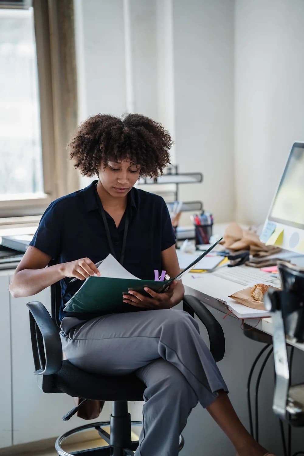 Conseillère noire étudiant les documents d'un dossier dans son bureau